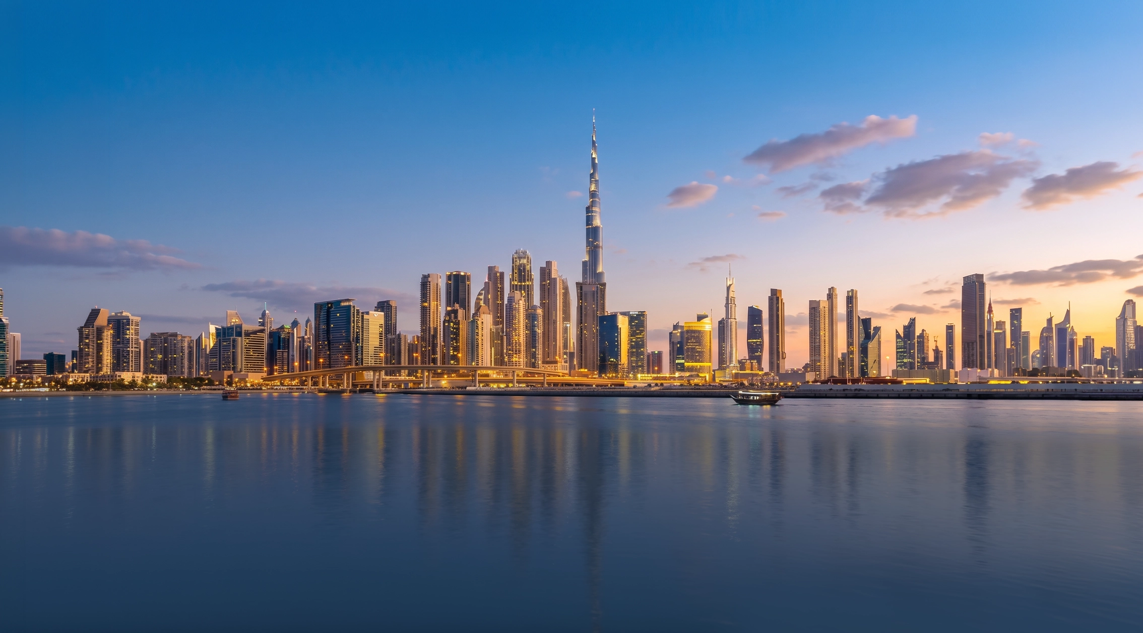 Dubai skyline across calm water at dusk